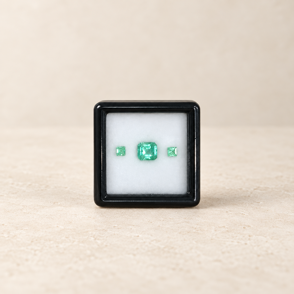 Three natural Brazilian emeralds on an ivory studio background
